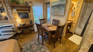 Interior acogedor de una cabaña con comedor, cama y baño.