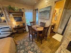 A cozy cabin interior with a dining area, a bed, and a bathroom.