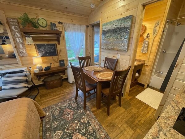 A cozy cabin interior with a dining area, a bed, and a bathroom.
