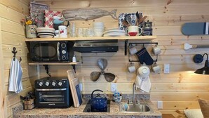 Una cocina compacta equipada con microondas, tostadora, hervidor y un lavabo.