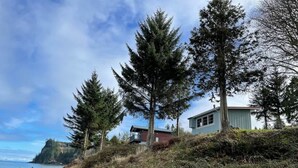 Una propiedad costera con una casa en una ladera, una playa rocosa y vistas al océano.
