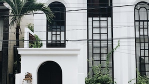 A white building with a black door, arched windows, and a black fence. - OriVista Stylish 3BR Villa Muzo in Seminyak, Pool, Wifi, Beach (Seminyak)