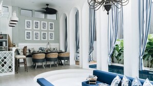 A modern living room with a blue sofa, dining area, and a view of a pool. - OriVista Stylish 3BR Villa Muzo in Seminyak, Pool, Wifi, Beach (Seminyak)