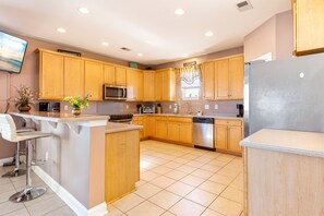 A modern kitchen with wooden cabinets, a stainless steel refrigerator, and a built-in microwave. - Waterfront Home with Multiple Decks, Central AC, WiFi, and Outdoor Shower (North Myrtle Beach)