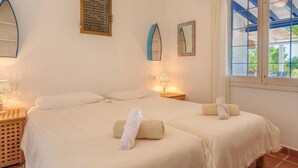 Een hotelkamer met twee bedden, een raam met uitzicht en een kleine tafel met een lamp.