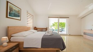 A bedroom with a wooden bed, a nightstand, a dresser, and a balcony with chairs. - Villa Maria by Interhome (Imotski)