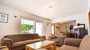 A spacious living room with two sofas, a glass coffee table, and a kitchen area visible through an open doorway. - Villa Maria by Interhome (Imotski)