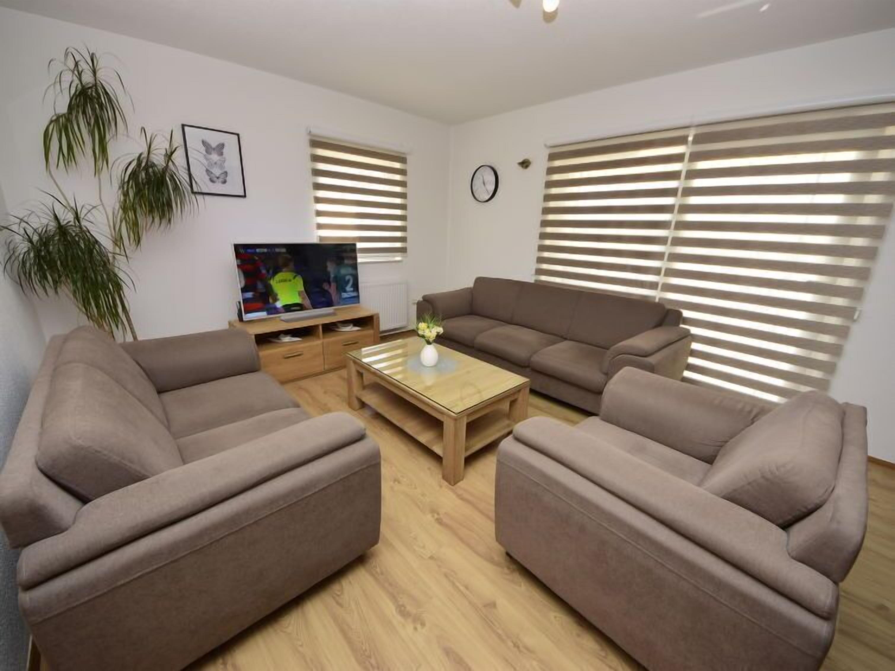 Ein Wohnzimmer mit zwei Sofas, einem Couchtisch, einem Fernseher und einer Pflanze.