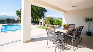 An outdoor patio with a pool, dining table, chairs, and a potted plant. - Villa Maria by Interhome (Imotski)