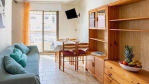 A cozy living room with a sofa, a dining table, and a wooden cabinet.