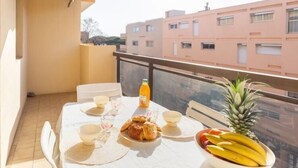 A balcony with a table set for breakfast, including bread, fruit, and a pineapple.