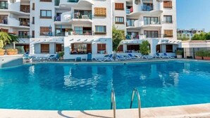 A modern hotel with a pool, featuring balconies with wooden shutters and a clear blue sky. - Carabela Front Beach & Pool by Interhome (Port d'Alcúdia)