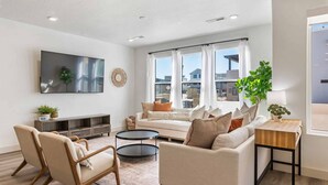 A modern living room with a sofa, chairs, a coffee table, and a TV mounted on the wall. - Mavericks Retreat by RedAwning (St. George)