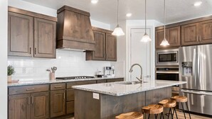 A modern kitchen with wooden cabinets, stainless steel appliances, and a granite countertop. - Mavericks Retreat by RedAwning (St. George)