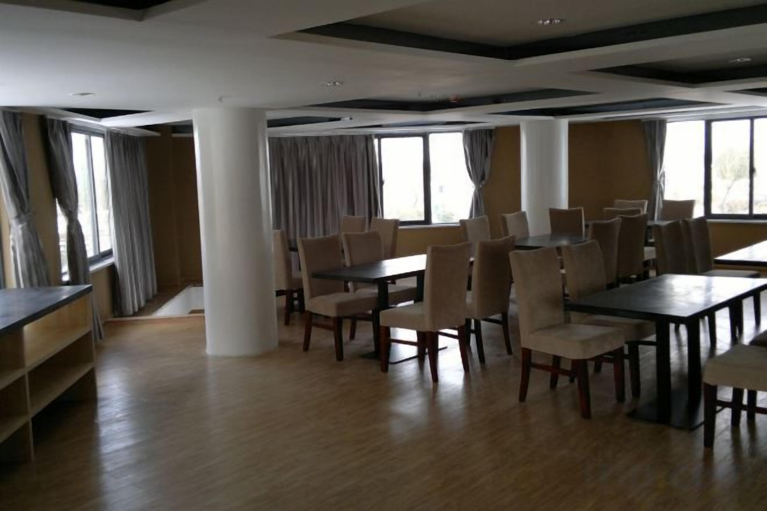 Un comedor amplio con varias mesas y sillas, ventanas grandes y un techo alto con vigas a la vista.