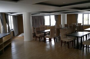 Un comedor amplio con varias mesas y sillas, ventanas grandes y un techo alto con vigas a la vista.