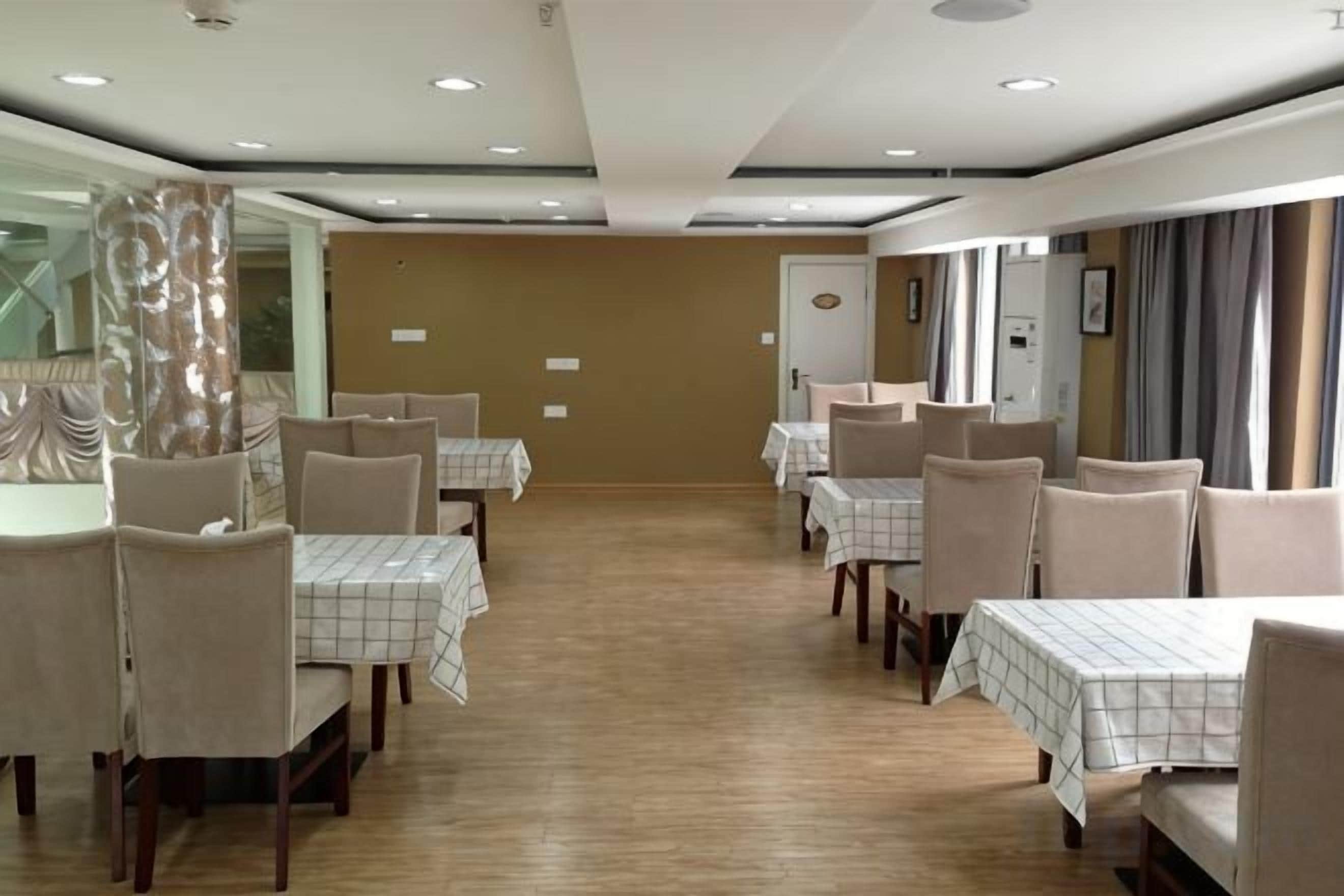 A dining area with tables and chairs, a wooden floor, and a mirror on the wall.