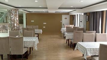 A dining area with tables and chairs, a wooden floor, and a mirror on the wall.