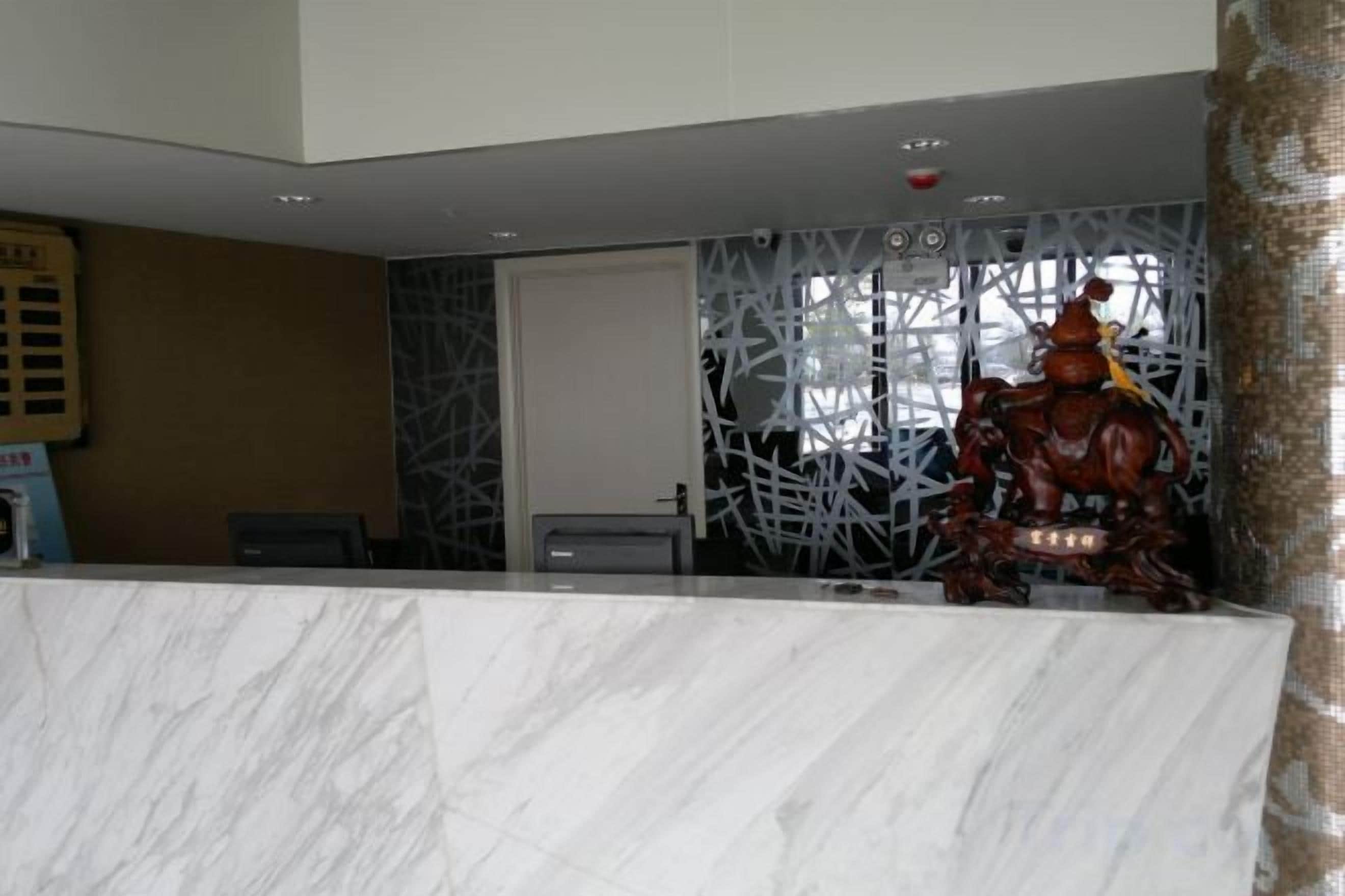 A reception desk with a marble top, a decorative wall with a geometric pattern, and a statue of a figure on horseback.