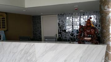 A reception desk with a marble top, a decorative wall with a geometric pattern, and a statue of a figure on horseback.