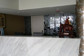 A reception desk with a marble top, a decorative wall with a geometric pattern, and a statue of a figure on horseback. - Zhonglang Express Hotel (Langxi)
