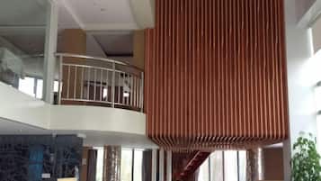 A multi-level interior with a central atrium, a staircase, and a railing.