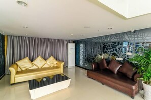 A modern living room with a sofa and a coffee table, a refrigerator, and a decorative wall. - Zhonglang Express Hotel (Langxi)