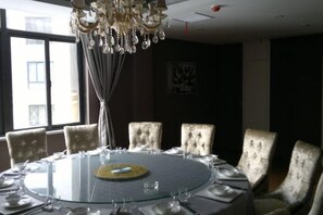A round table with chairs, a chandelier, and a window with curtains. - Zhonglang Express Hotel (Langxi)
