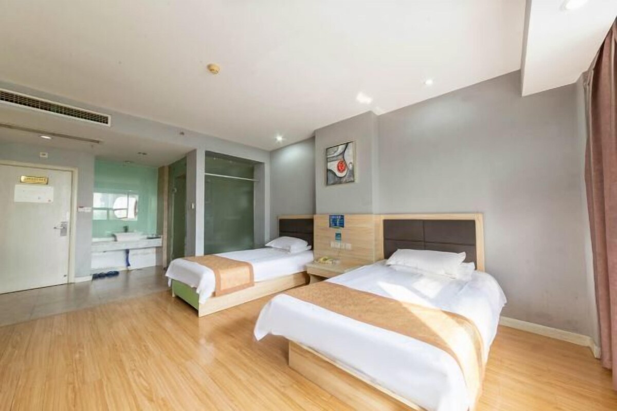 Habitación de hotel con dos camas, baño y vistas al exterior.