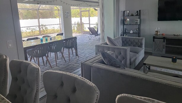 An open-plan living area with a patio, seating, and a TV. - Endless Summer Villa with heated salt water pool (Port Charlotte)