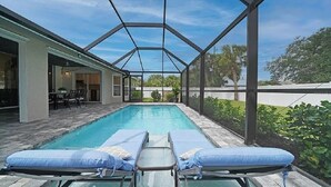 A covered swimming pool with lounge chairs and a patio area. - Endless Summer Villa with heated salt water pool (Port Charlotte)