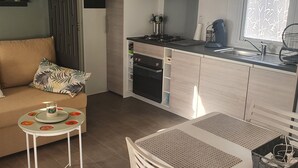A compact living space with a kitchenette, a dining area, and a sofa. - Zenitude AZ75 (Frejus)
