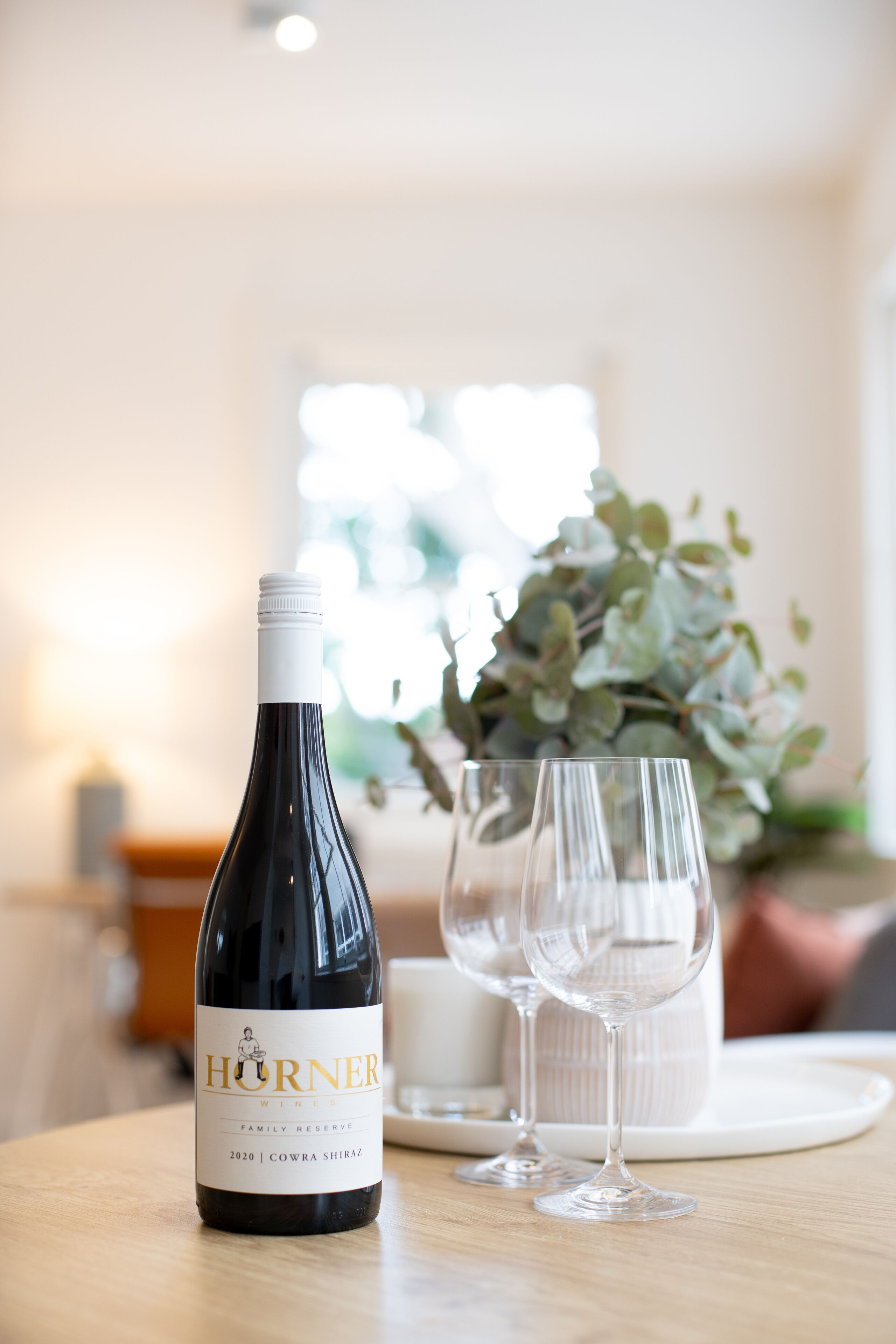 A bottle of wine and two glasses on a table.