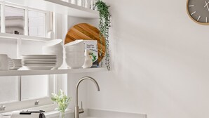 A modern kitchen with white cabinetry, a stainless steel sink, and a clock on the wall. - Mulwarree Avenue Apartments by Urban Rest (Randwick)