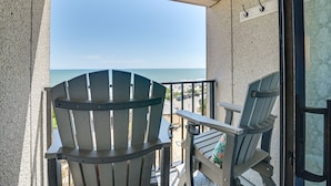 Un balcone con due poltrone Adirondack, un tavolino e vista sull'oceano.