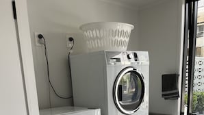 A compact laundry area with stacked appliances including a washer, dryer, and refrigerator. - Location Location! T Two on Whakaue  (Rotorua)