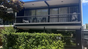 A modern building with a balcony, large windows, and a well-maintained garden. - Location Location! T Two on Whakaue  (Rotorua)