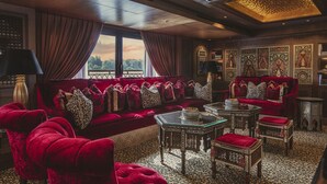 Una habitación lujosa con un sofá rojo, un suelo estampado y decoraciones ornamentales en las paredes.