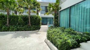A modern building with a pool, surrounded by well-maintained greenery and palm trees. - Infinity Aonang Krabi Hotel (Krabi)