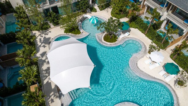 An aerial view of a resort with multiple swimming pools, palm trees, and lounge areas. - Infinity Aonang Krabi Hotel (Krabi)
