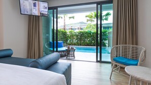 A modern hotel room with a large bed, a sofa, a wicker chair, a small table, and a TV mounted on the wall. - Infinity Aonang Krabi Hotel (Krabi)