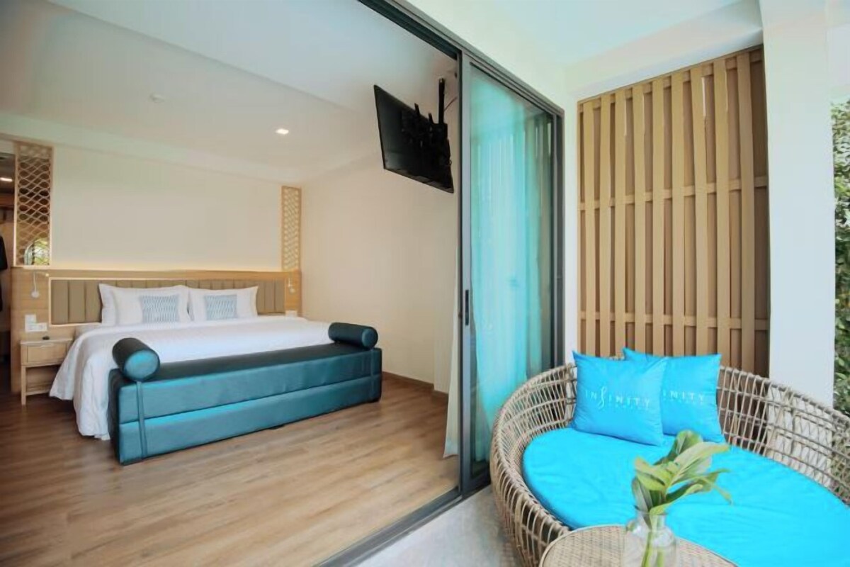 A bedroom with a bed, a sofa, and a television on the wall.