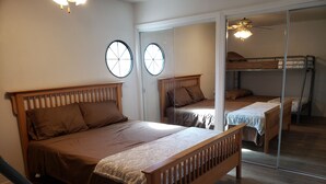 A bedroom with a wooden bed, a mirror, and a bunk bed in the background.