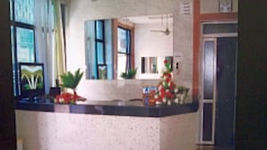 Un área de recepción con mostrador, plantas en macetas y una puerta a la derecha.