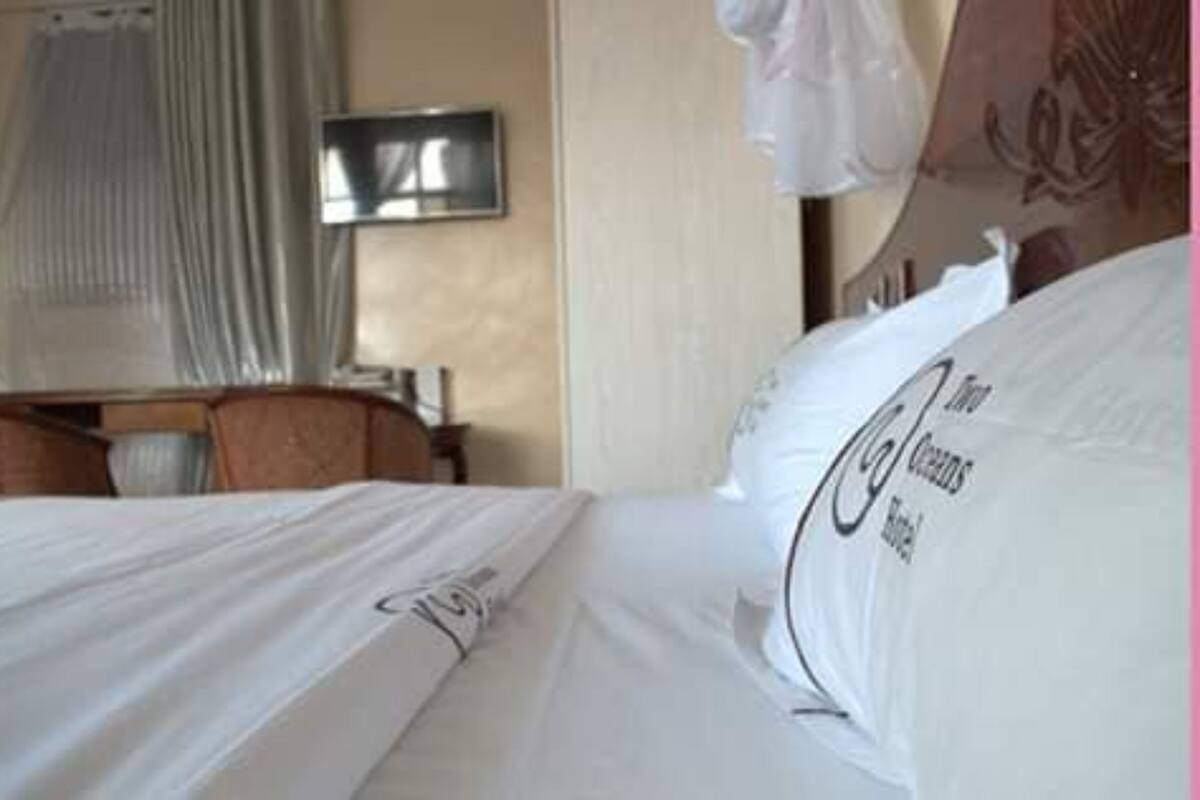 A hotel room with a neatly made bed, a television on the wall, and a curtain.