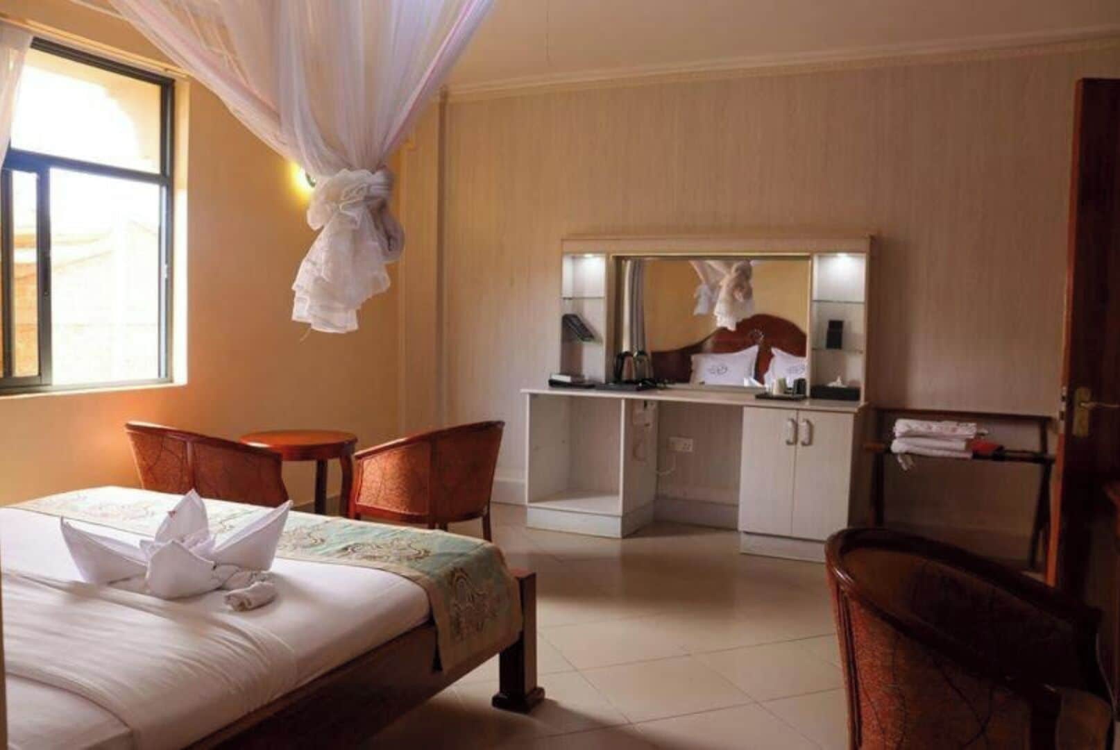 Une chambre d’hôtel comprenant un lit, un bureau, une chaise, un miroir et une armoire.