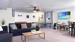 Ein modernes Wohnzimmer mit Sofa, Couchtisch und Dartscheibe an der Wand.