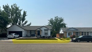 Eine Wohnstraße mit zwei Häusern, eines mit Garage und das andere mit Vorgarten.