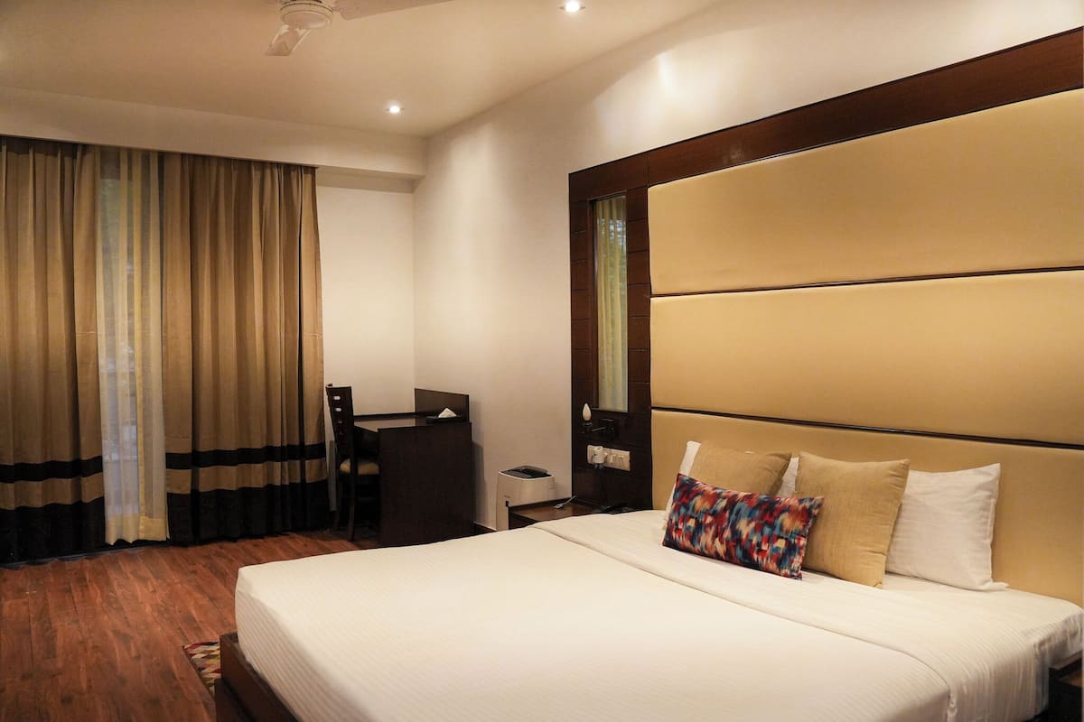 Una habitación de hotel con una cama grande, un escritorio y una silla.