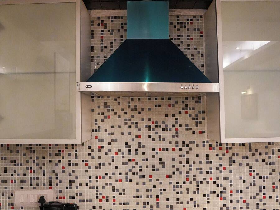 A kitchen with a tiled backsplash, a stove, a coffee maker, and a kettle.